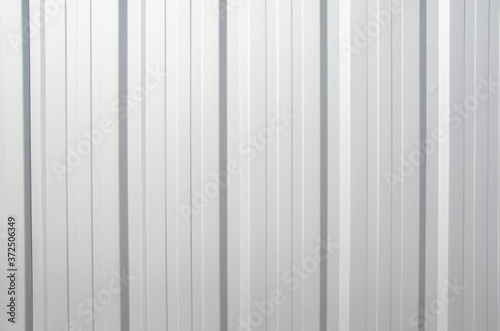 Metal tile fence background. Fence from corrugated board. Gray slate background. Zinc metal sheet texture. Steel panel of the enclosing wall. Silver background with copy space.