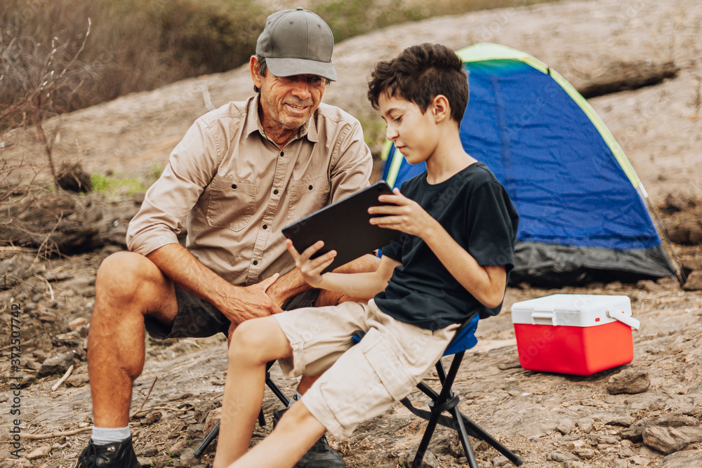 Latin grandfather and grandson camping. Concept of grandparents and grandchildren in outdoor activities.
