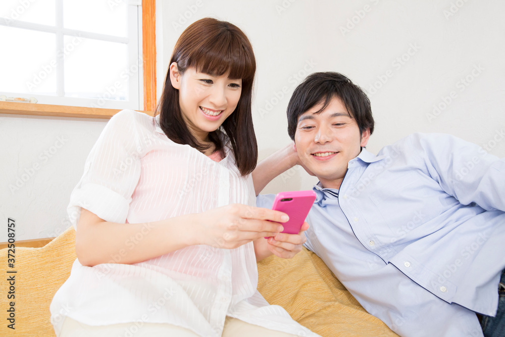 Fototapeta premium 寝転びながらスマホを見る夫婦