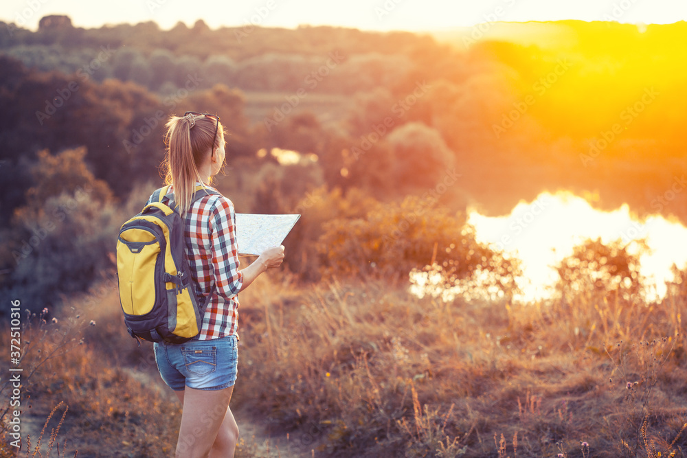 Φωτογραφία caucasian woman tourist with a map and a backpack on a hike navigates the terrain