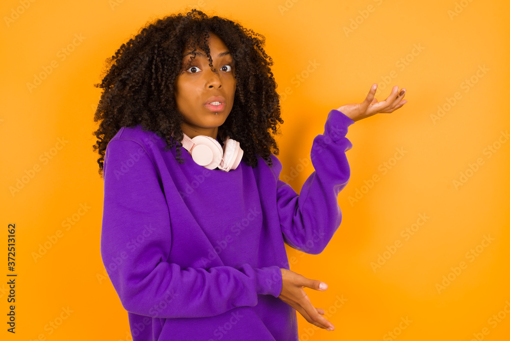 Beautiful European girl pointing aside with both hands showing something strange and saying: I don't know what is this. Standing against gray background. Advertisement concept. Beautiful European girl pointing aside with both hands showing something strange and saying: I don't know what is this. Standing against gray background. Advertisement concept.