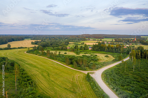 aerial view of Latvian rural landscape with agricultural fields, forests and roads at sunset