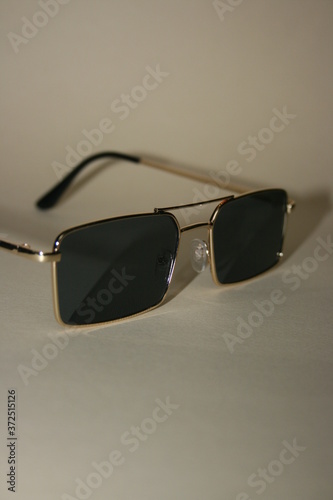 black sunglasses with a gold frame on a beige background