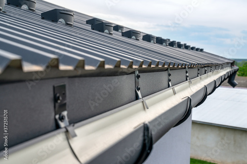 . Gutter system for a metal roof. Holder gutter drainage system on the roof. photo