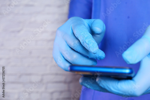 doctor's hand in protective gloves using a smartphone.