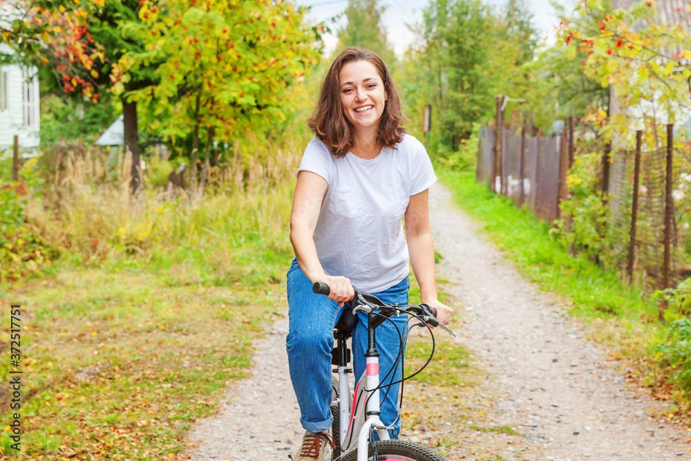 Fototapeta premium Young woman riding bicycle in summer city park outdoors. Active people. Hipster girl relax and rider bike. Cycling to work at summer day. Bicycle and ecology lifestyle concept.