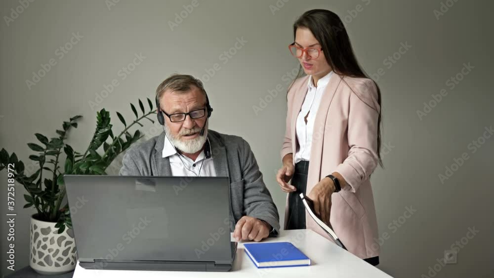 Young manager helps a senior employee with computer work in the office. Young manager helps a senior employee with computer work in the office.