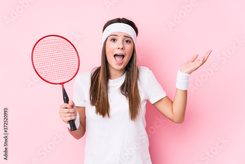 Young caucasian woman playing badminton isolated receiving a pleasant surprise, excited and raising hands. © Asier
