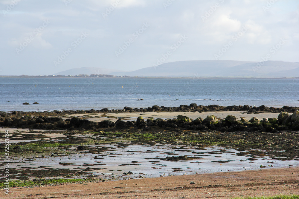 Sea through rocks and sand and mountains in the background in Galway Sea through rocks and sand and mountains in the background in Galway