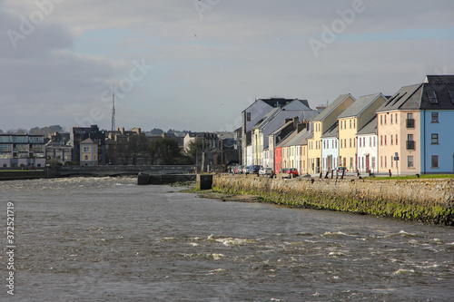 Typical colorful houses with sea next to it and cloudy skies in Galway, Ireland