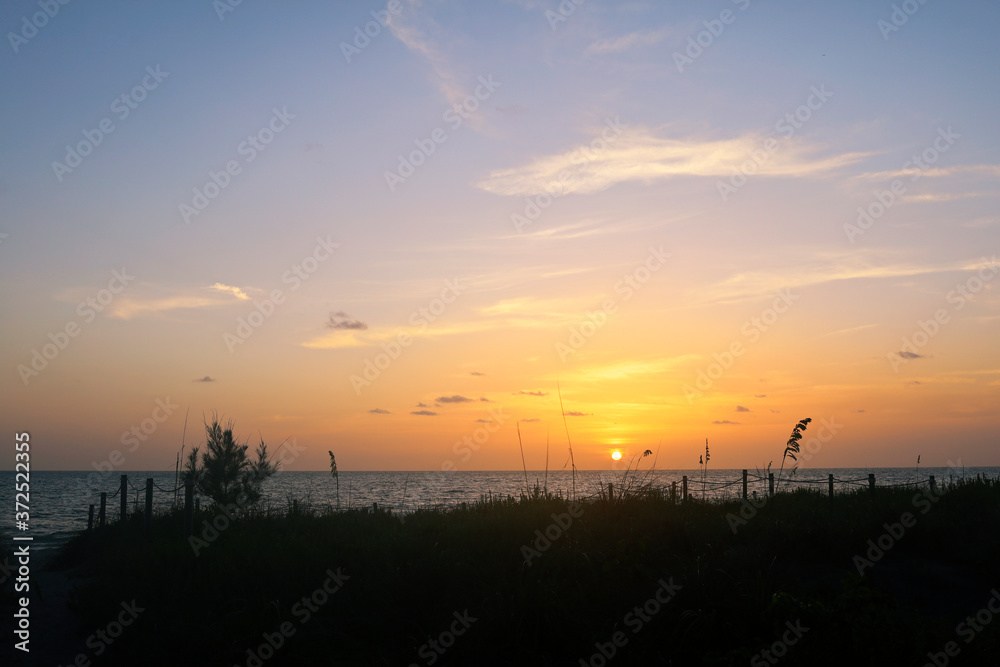 Sunset in Captiva Sanibel Island, Florida. Gulf of Mexico at dusk. Sun sets over beach on Captiva Island over calm waters. Illuminated dreamy summer sunset.