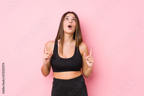 Young fitness caucasian woman isolated pointing upside with opened mouth.