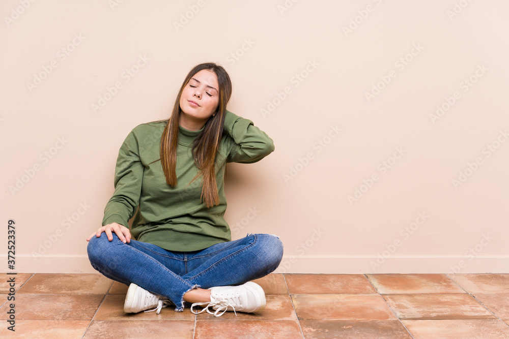 Young caucasian woman sitting on the floor isolated suffering neck pain due to sedentary lifestyle.