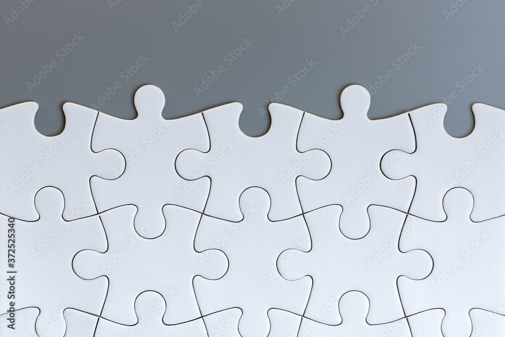 Obraz premium White jigsaw puzzle pieces on gray background