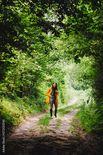 woman in yellow raincoat walking by rainy forest