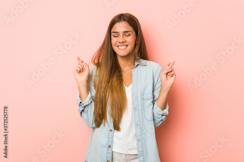 Obraz na plátne Young slim woman crossing fingers for having luck
