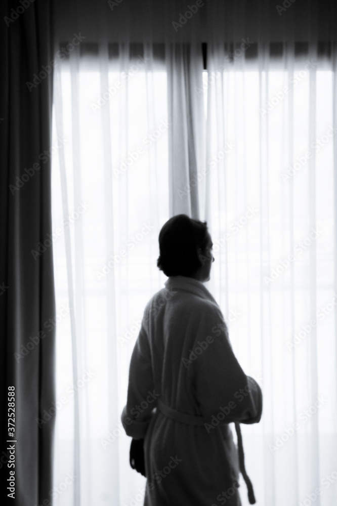 Silhouette of woman with bathrobe in front of a window