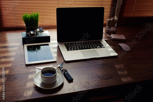 Mock up of office or home desktop with accessories and work tools, laptop computer and digital tablet with copy space screen, plant pot, cup of coffee, empty touch pad, modern hipster workspace table