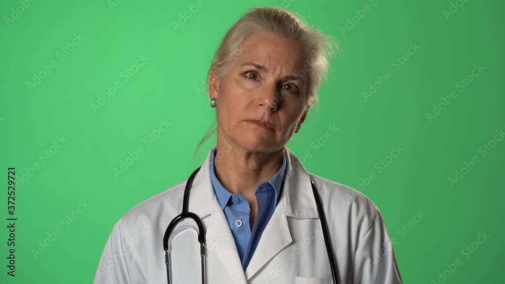Push in portrait of experienced gray haired female doctor listening with empathy to a patient. Shot on green screen. Push in portrait of experienced gray haired female doctor listening with empathy to a patient. Shot on green screen.