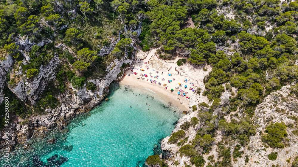 Beautiful aerial view of Mediterranean white sand beach and turquoise water and a boat in Menorca Spain, Cala Macarella, aerial top view drone photo