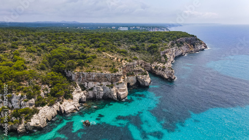 Beautiful aerial view of Mediterranean white sand beach and turquoise water and a boat in Menorca Spain, Cala Macarella, aerial top view drone photo