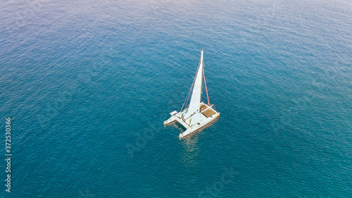 Aerial top view to catamaran sailing in open sea on a blue water at windy day. Drone view