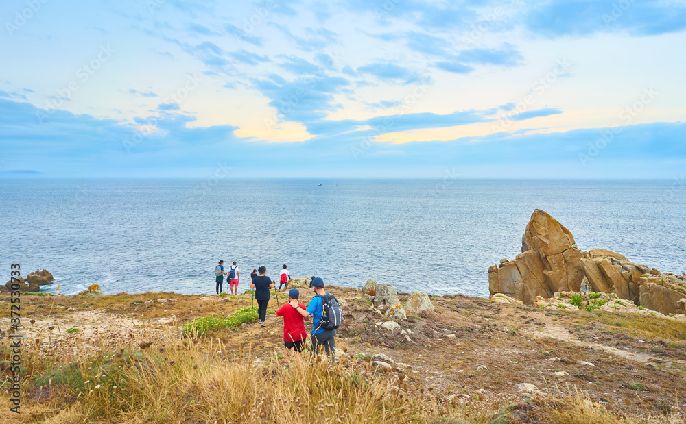 Family looking at the sea at sunset in a landscape of the coast of Galicia. Spain
