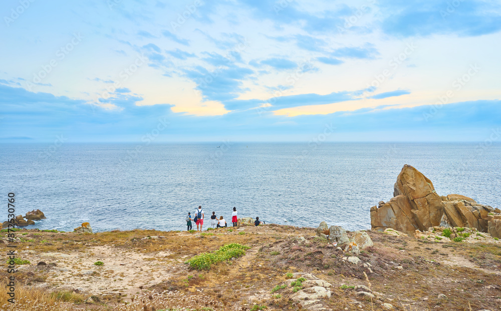 Family looking at the sea at sunset in a landscape of the coast of Galicia. Spain