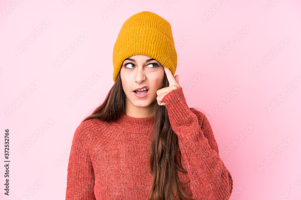 Young caucasian woman wearing a wool cap showing a disappointment gesture with forefinger.