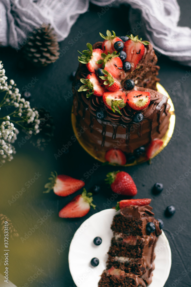  plano cenital de un Ponqué húmedo de chocolate, relleno de fresas con crema, decorado con brigadeiro de chocolate y ganache de chocolate y arándanos