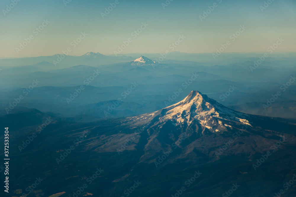 An early morning aerial shot from a commercial airliner of Mt Hood and Mt Jefferson and layered hills near Portland, Oregon.