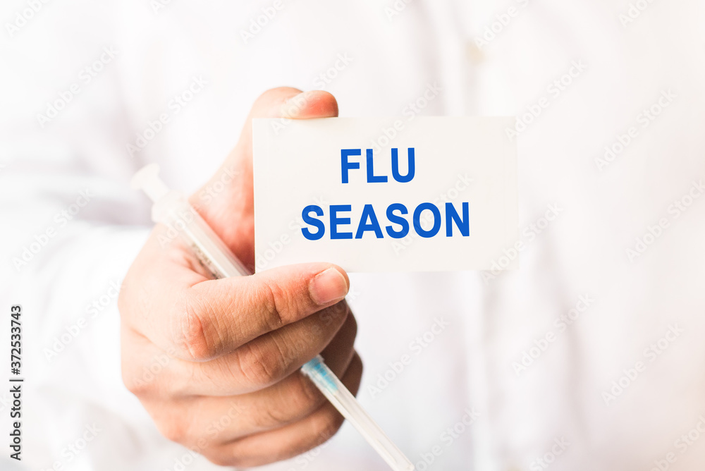Word flu season on a white background with a syringe in hand. Medicine concept Word flu season on a white background with a syringe in hand. Medicine concept