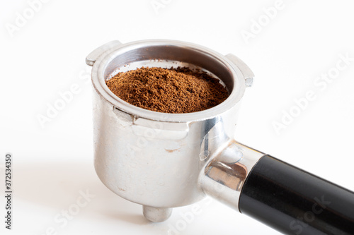 Portafilter filled with ground coffee on white background