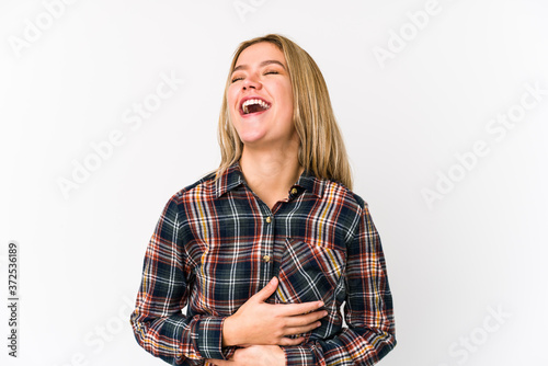 Young blonde caucasian woman isolated laughs happily and has fun keeping hands on stomach. © Asier
