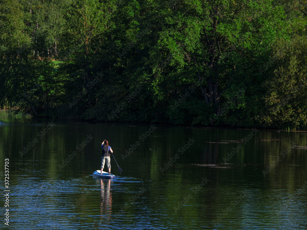 Woman sailing on beautiful calm green lagoon. Summer holidays vacation travel. SUP Stand up paddle board