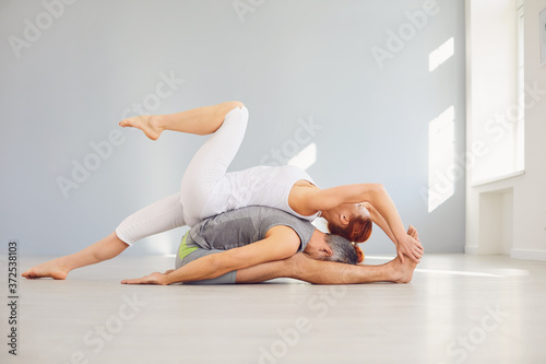 Yoga couple practice acro yoga on the floor in a studio class.