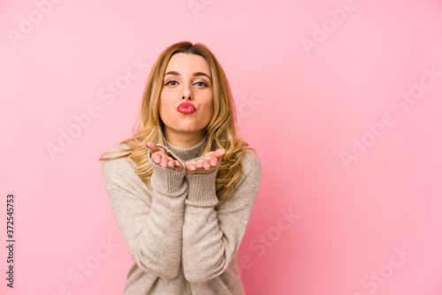 Young blonde cute woman wearing a sweater isolated folding lips and holding palms to send air kiss.