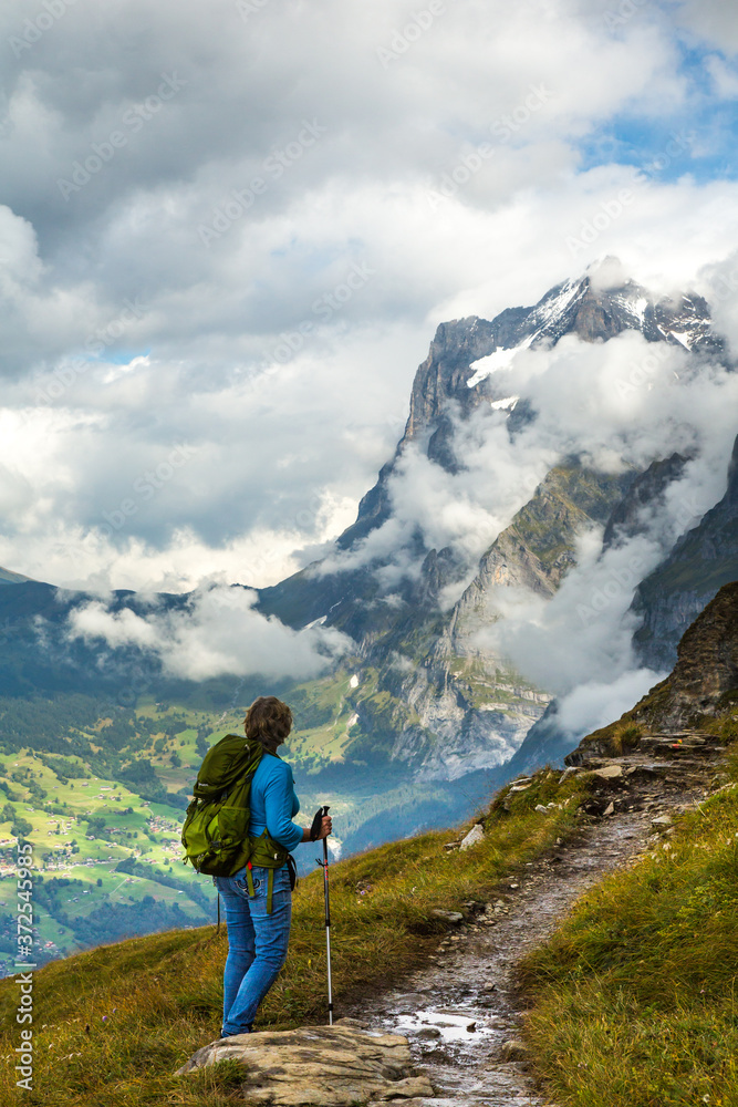 A lone woman hiker on the Eiger trail in the Alps mountains above Lauterbrunnen, Switzerland.
