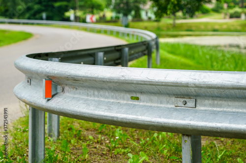asphalt road bend with a metal protection barrier in the foreground