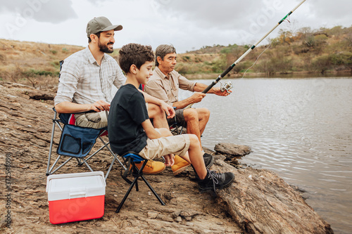 Male members of three generation family fishing together
