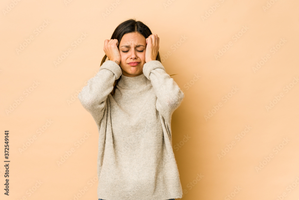 Young woman isolated on beige background crying, unhappy with something, agony and confusion concept.