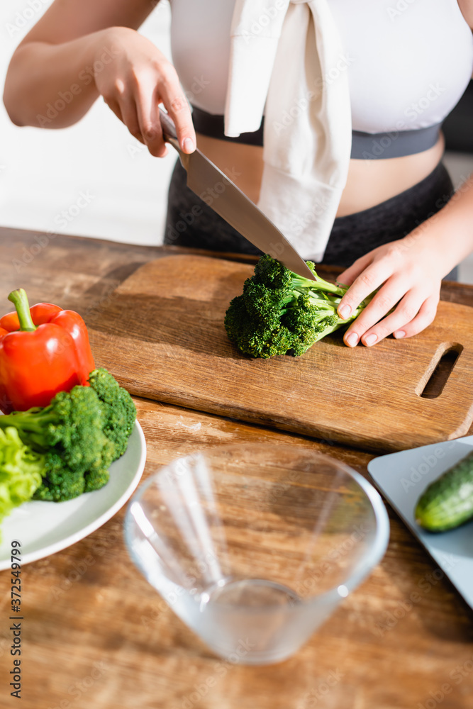cropped view of woman cutting fresh broccoli on chopping board near vegetables cropped view of woman cutting fresh broccoli on chopping board near vegetables