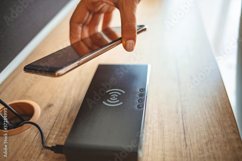 Woman placing smart phone on wireless charger. Caucasian woman wirelessly charging a mobile phone. Woman putting her smartphone on wireless charger Wireless Charging Port