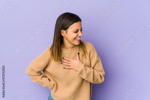 Young woman isolated on purple background laughing keeping hands on heart, concept of happiness.