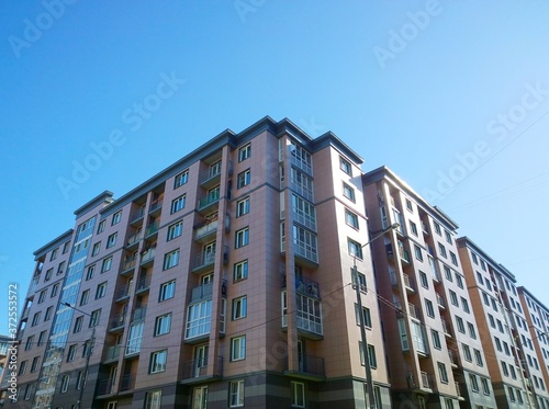 Facade of new multi-story residential building. Sale and rental apartments. Housing affordability and development. Cityscape. City living. Real estate investing. Mortgage concept. Blue sky background 