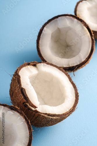 Coconut fruits in row on blue vibrant plain background, abstract food tropical concept, angle view macro