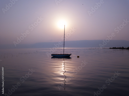 Sunrise over the lake. Boat floating on the calm water under amazing sunset.