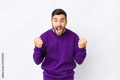 Young caucasian man against a white background isolated cheering carefree and excited. Victory concept.