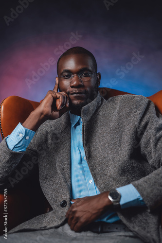 A casual leather chair and male blackskinned business person on it photo