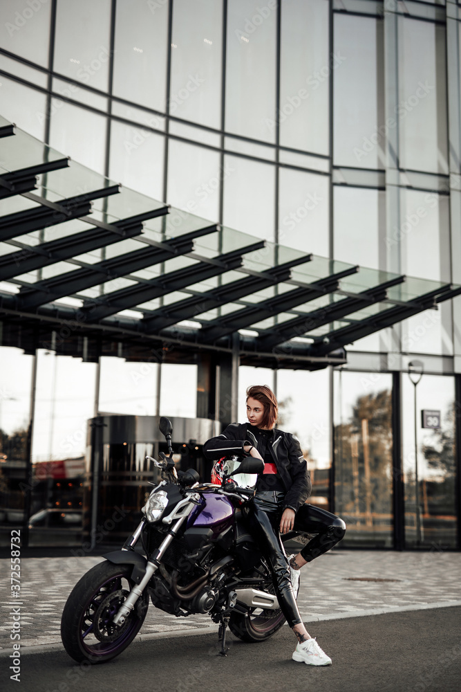 Stylish girl lying on a purple motorbike with a safety red and black helmet